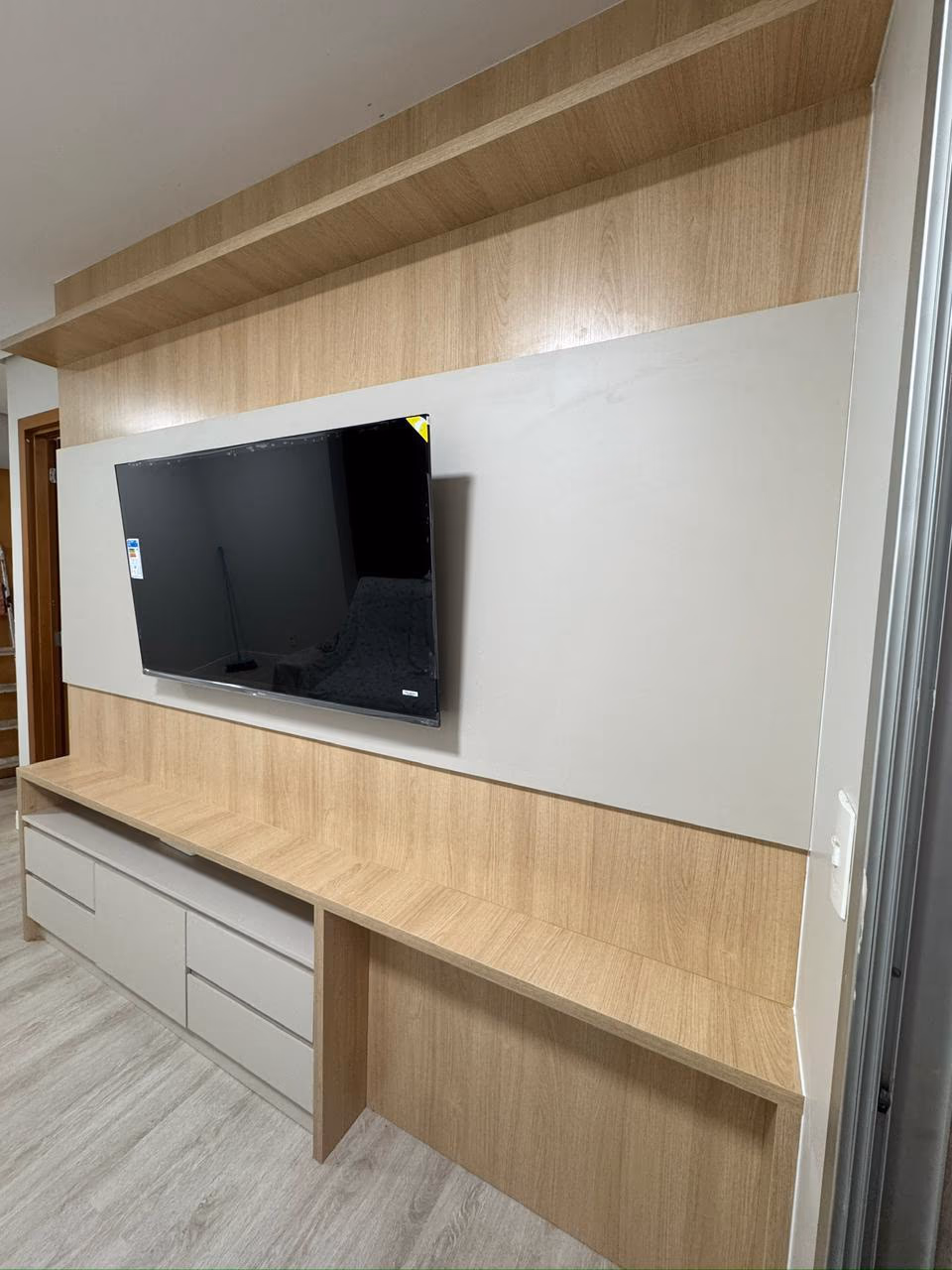 Foto do projeto: Sala com painel de TV bege e madeira, em Brasília, DF